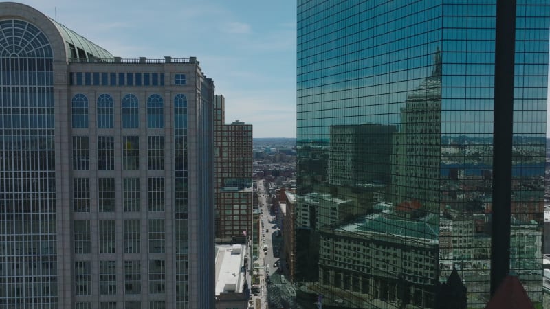 Glossy glass facade of John Hancock Tower reflecting surrounding buildings. Forwards fly above city. Boston, USA