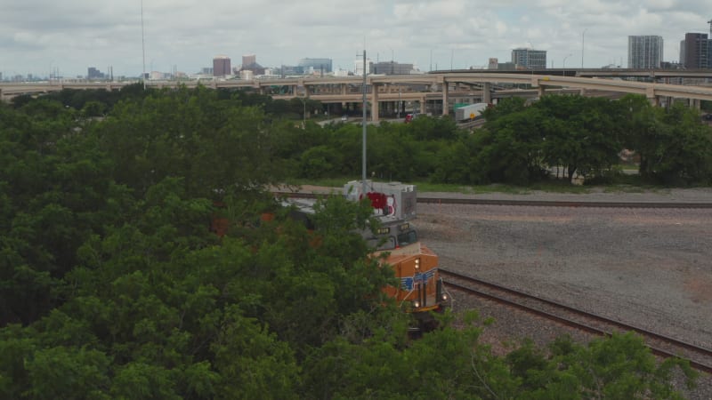 Aerial view of front of diesel locomotive standing of track. Panning view gradually revealing train engine. Highway intersection in background. Dallas, Texas, US