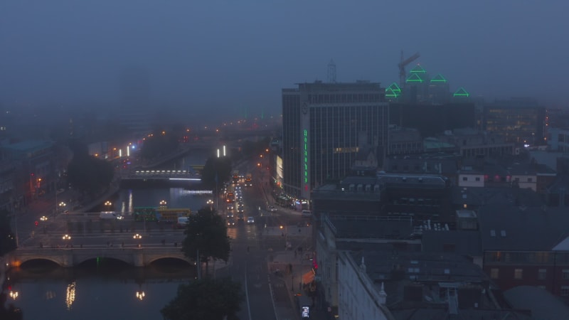 Aerial footage of evening city at Liffey river. Misty weather after sunset. Traffic in town centre. Dublin, Ireland