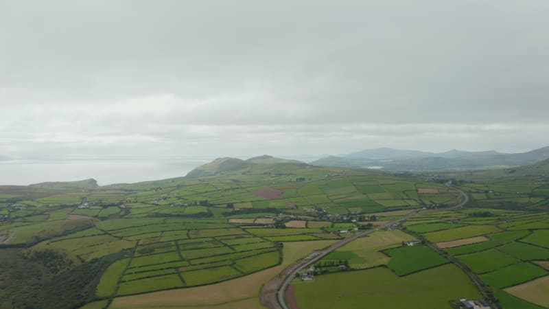 Aerial panoramic footage of agricultural landscape at seaside. Road passing through countryside with green fields and meadows. Ireland