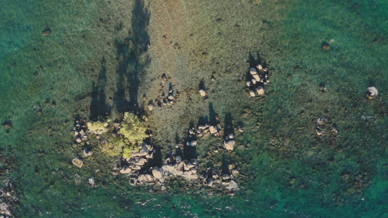 Top down view of waves splashing on the rocks of emerald lake