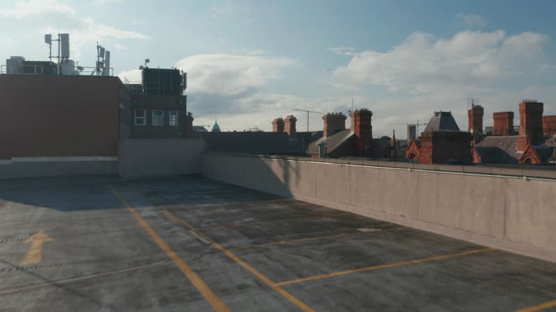 Backwards descending shot of historic city, landing on rooftop car park. Afternoon sun with long shadows. Dublin, Ireland