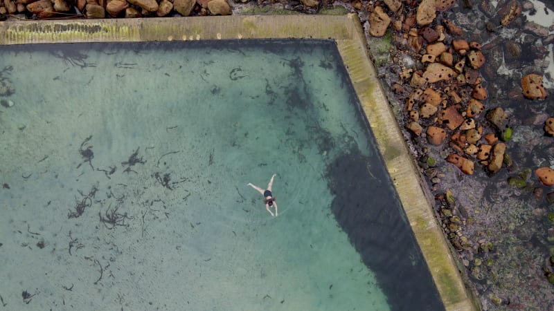 Aerial view of woman swimming in Glencairn pool, Cape Town, South Africa.