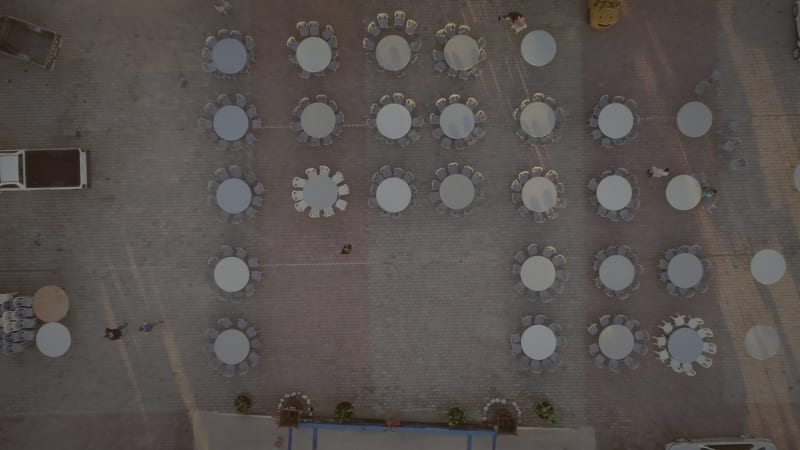 Aerial view of people preparing tables and chairs for a outdoor party.