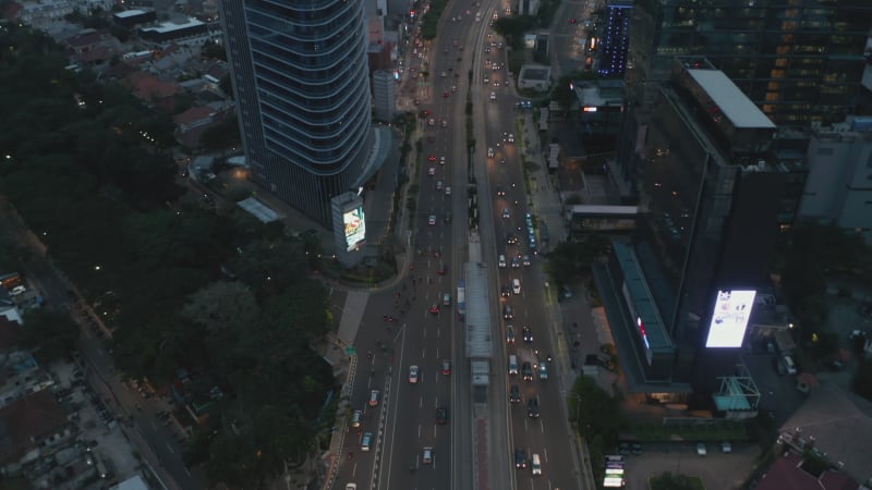 Aerial tilting shot following traffic on a multi lane highway into the modern city center with skyscrapers in Jakarta