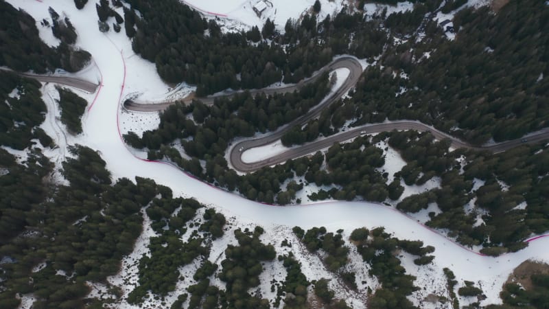 Aerial view of a ski track crossing a winding mountain road