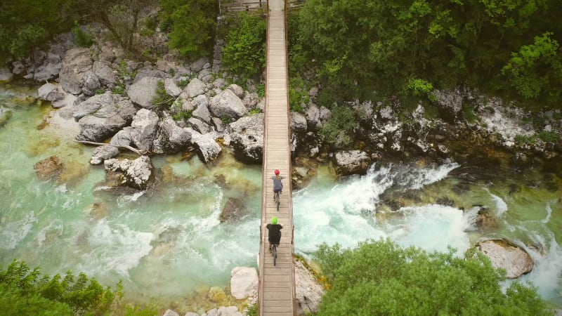 Aerial view of couple crossing a wooden bridge on bicycles.