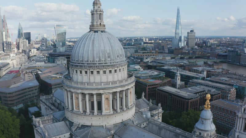 Close up of large dome of church. Backwards reveal of Saint Pauls Cathedral and surrounding buildings. Group of modern skyscrapers in background. London, UK