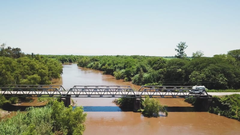 Aerial view of campervan crossing a dirty river.