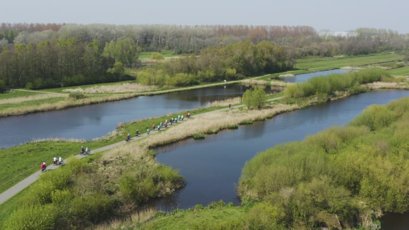 Group of cyclists casually cycling along riverfront in Netherlands