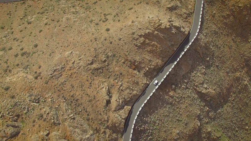 Aerial view of a car driving on a winding mountain road.