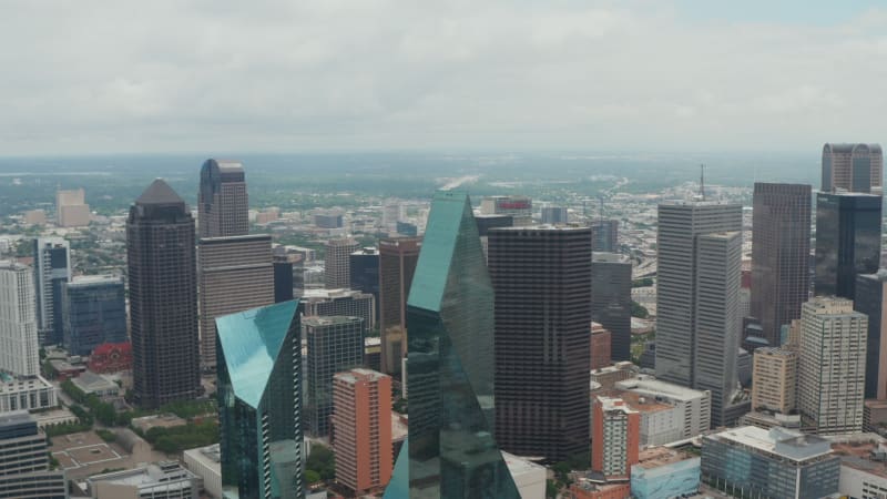 Forwards flying drone towards modern tall buildings at Fountain place with glass facades and irregular shape. Aerial view of downtown. Dallas, Texas, US