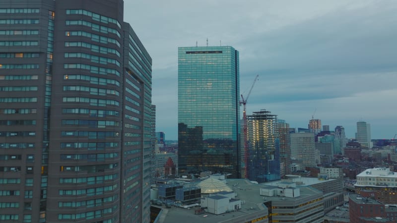 Forwards fly between high rise office towers. Glossy glass skyscraper reflecting surrounding buildings. Downtown at dusk. Boston, USA