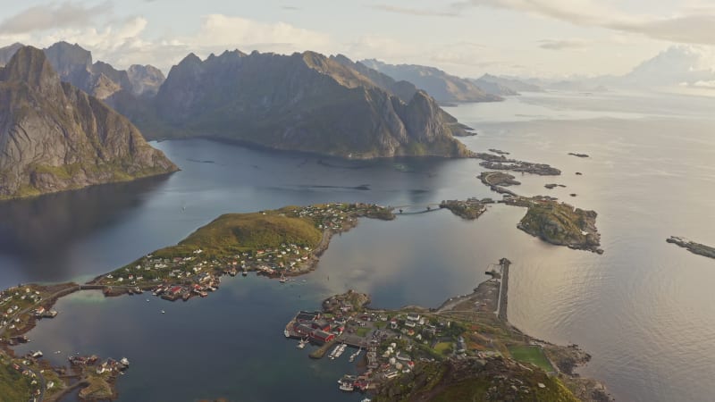 Slow moving view of island towns connected by bridges surrounded by huge mountain peaks in Reine, Norway.