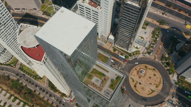 Fly over modern tall Paradox Torre building. Camera tilt down shot. Top down view of surrounding streets and park. Mexico City, Mexico.