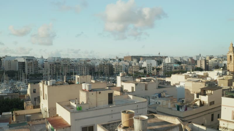 Dolly forward over Roof Terrace revealing Port of Mediterranean City Town on Malta Island in Brown Beige and Blue Color, Aerial View