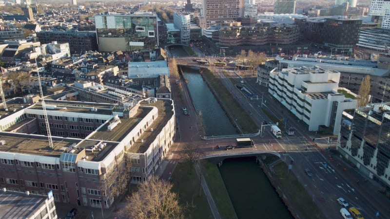 Flyover Dutch canal in downtown Utrecht, along modern office buildings and bridge in the Netherlands.