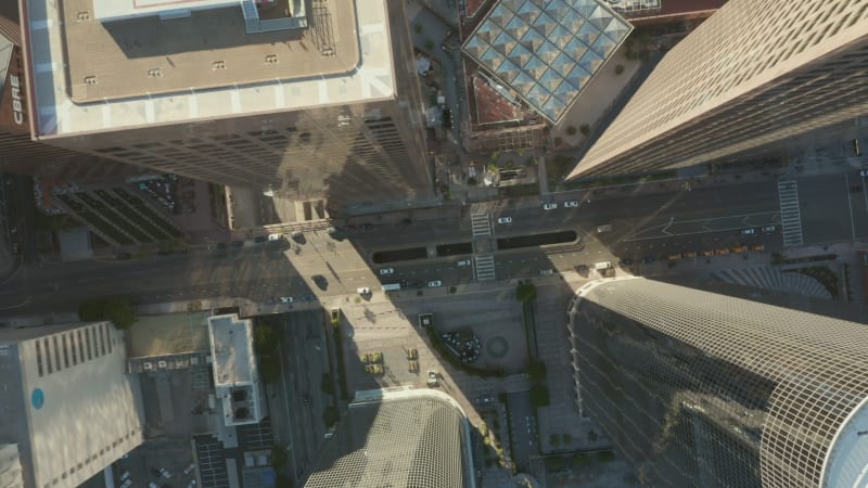 Slow uplifting birds eye View flight over Downtown Los Angeles California Grand Avenue in beautiful Sunrise Light with view of skyscraper rooftops and car traffic passing