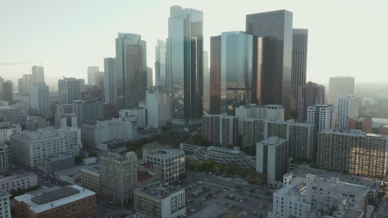 Flying towards Downtown Los Angeles, California Skyline with look at houses and street traffic at beautiful blue sky and sunny day