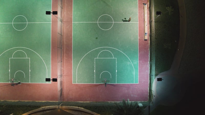 Aerial view of people playing at basketball court during the night.