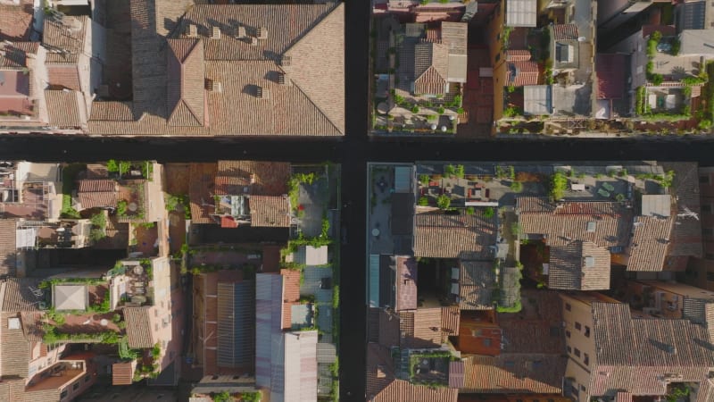 Overhead ascending shot of old residential houses and narrow streets in city centre. Terraces with green plants. Rome, Italy