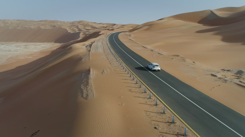 Aerial view of white car in clean road in the desert.