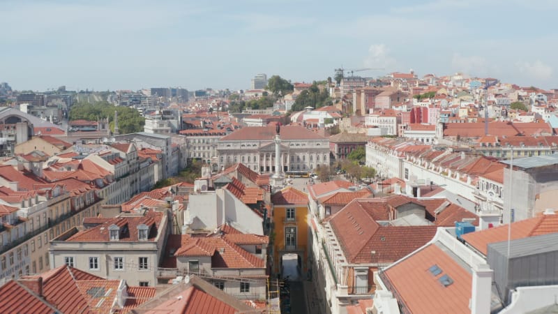 Aerial view of historic town center, King Pedro IV Square with Column of Pedro IV and Queen Maria II National Theatre. Drone camera flying forward and tilts down. Lisbon, capital of Portugal.