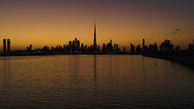 Aerial view of Dubai skyscrapers silhouettes at sunset.