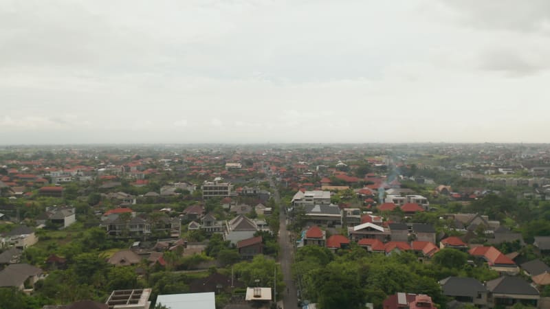 Descending aerial view of streets at Canggu city in Bali. Panoramic wide view of residential houses and small homes at famous tourist resort in tropical Bali