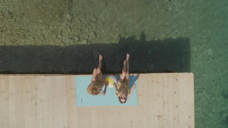 Aerial view of two women sits on wooden deck in Panagopoula.