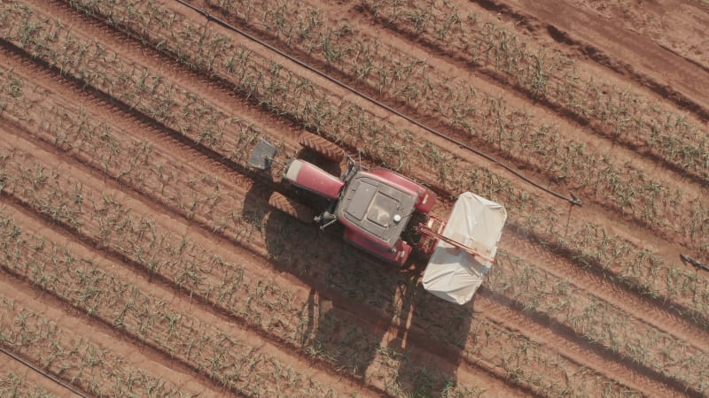 Tractor hauling a Two disc Fertilizer spreader in a large field, Aerial follow footage.