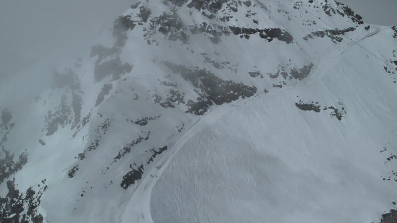 Aerial shot tilting up and down above ski slope revealing Cime Caron lift in Val Thorens