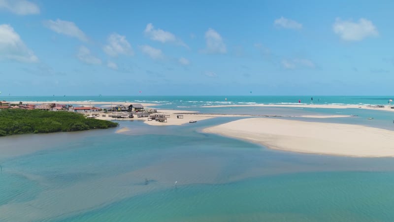 Aerial view of people practicing kitesurfing near a natural sand bank.