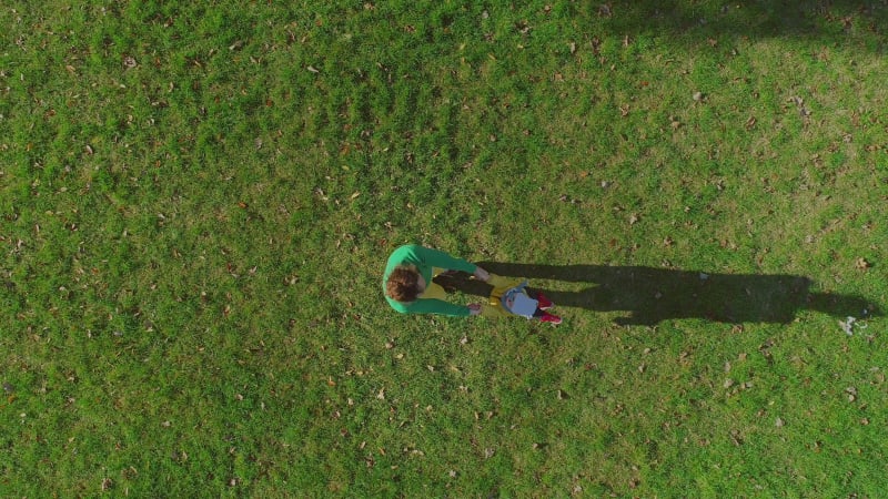 Aerial view of father rotating infant son at public playground.