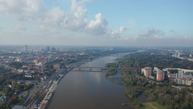 Aerial panoramic footage of city around wide river. Heavy traffic on riverbank roads. Warsaw, Poland