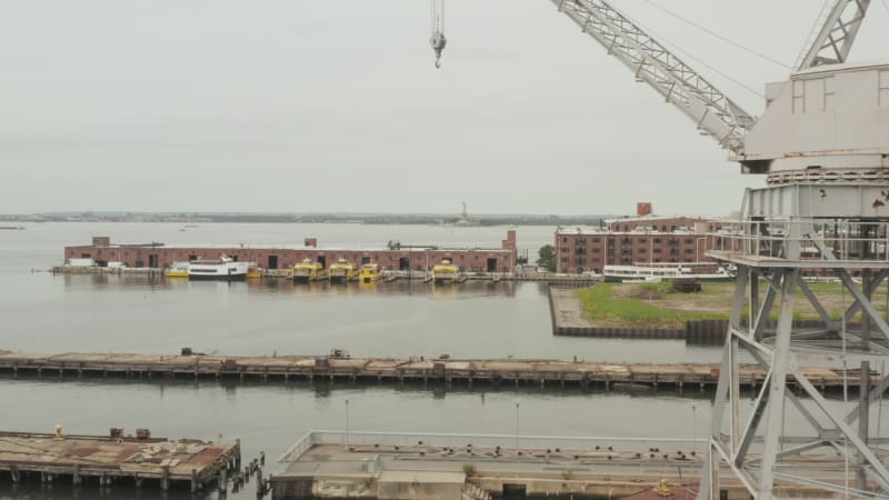 Flying over warehouses in docks of New York City with river and skyline view in