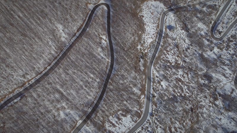 Aerial view of a car road surrounded by snow and trees.