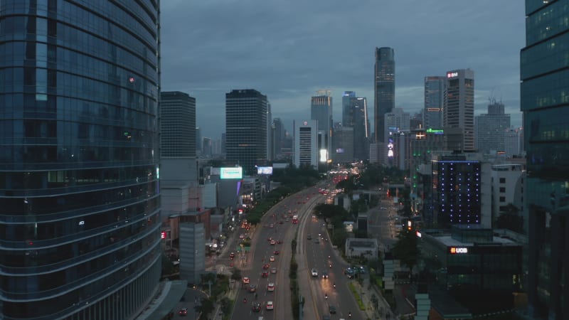 Aerial pedestal descending shot of night traffic on a multi lane road through Jakarta city center