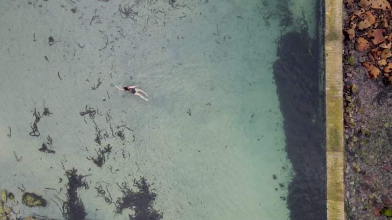 Aerial view of woman swimming in Glencairn pool, Cape Town, South Africa.