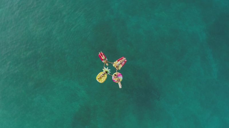 Aerial view group of women holding hands on inflatable mattress.