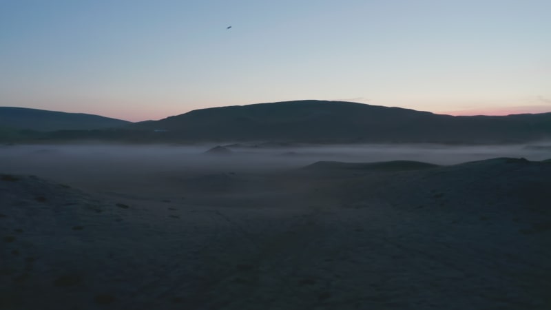 Orbit aerial view of foggy and misty highlands at sunset in Iceland. Stunning moonscape panorama of moody autumnal countryside. Beauty in nature. Icelandic foggy countryside