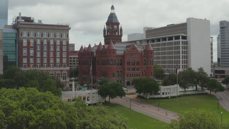 Aerial view of building in historic castle style with tower and few turrets. Old Red Museum of Dallas County between modern multi-storey office blocks downtown. Dallas, Texas, US