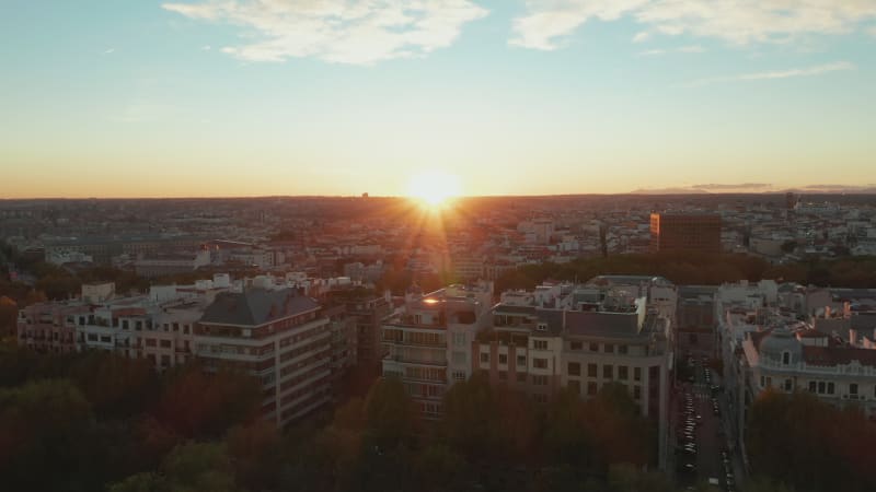 Pull ball footage of large multistorey apartment buildings at city park. Revealing cityscape against setting sun.