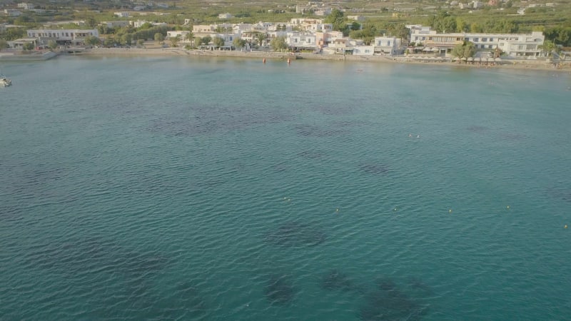 Aerial view of sailboats parked in blue waters on a beach.