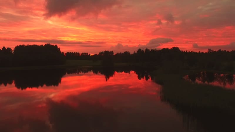 Aerial view of a lake with reflection of the pink sky.