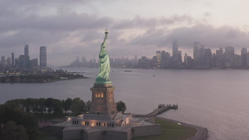 Umkreisende Freiheitsstatue, wunderschön beleuchtet im frühen Morgenlicht, Aerial von New York City