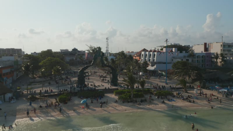 Flyover above Playa del Carmen. Drone flying next to the Portal Maya sculpture and revealing the Mexican holiday resort