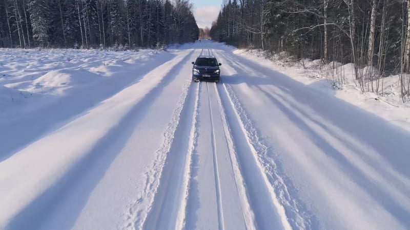 Aerial view of a car reversing in the snowy forest in Estonia