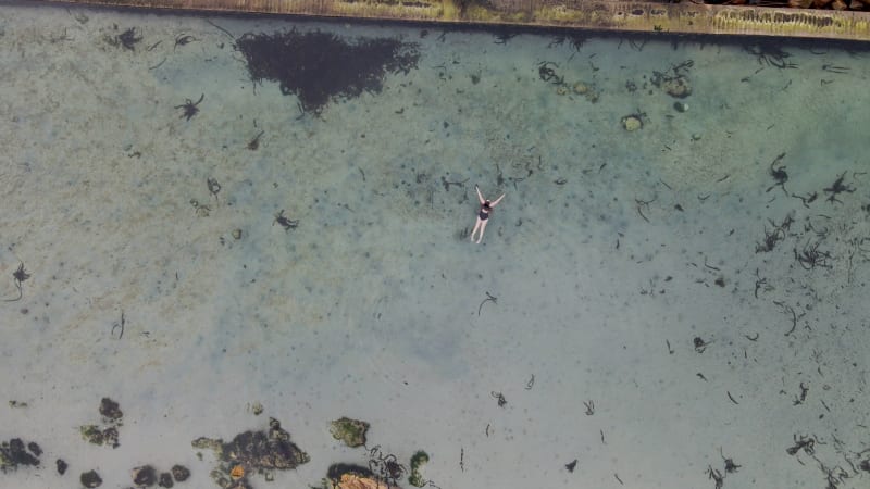 Aerial view of woman swimming in Glencairn pool, Cape Town, South Africa.