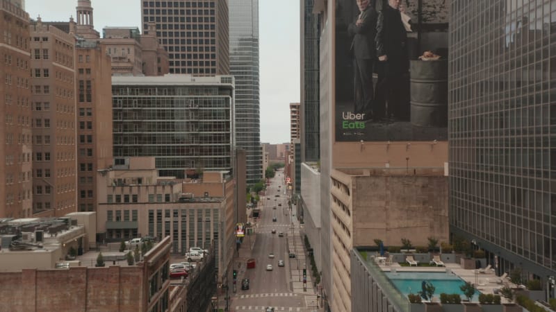 Forwards reveal shot of street with various heights of buildings around. Fly between multi-storey office blocks. Dallas, Texas, US